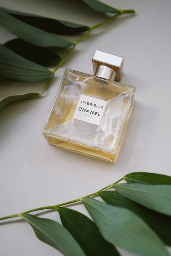 Gabrielle Essence Eau De Parfum bottle on a table with green leaves